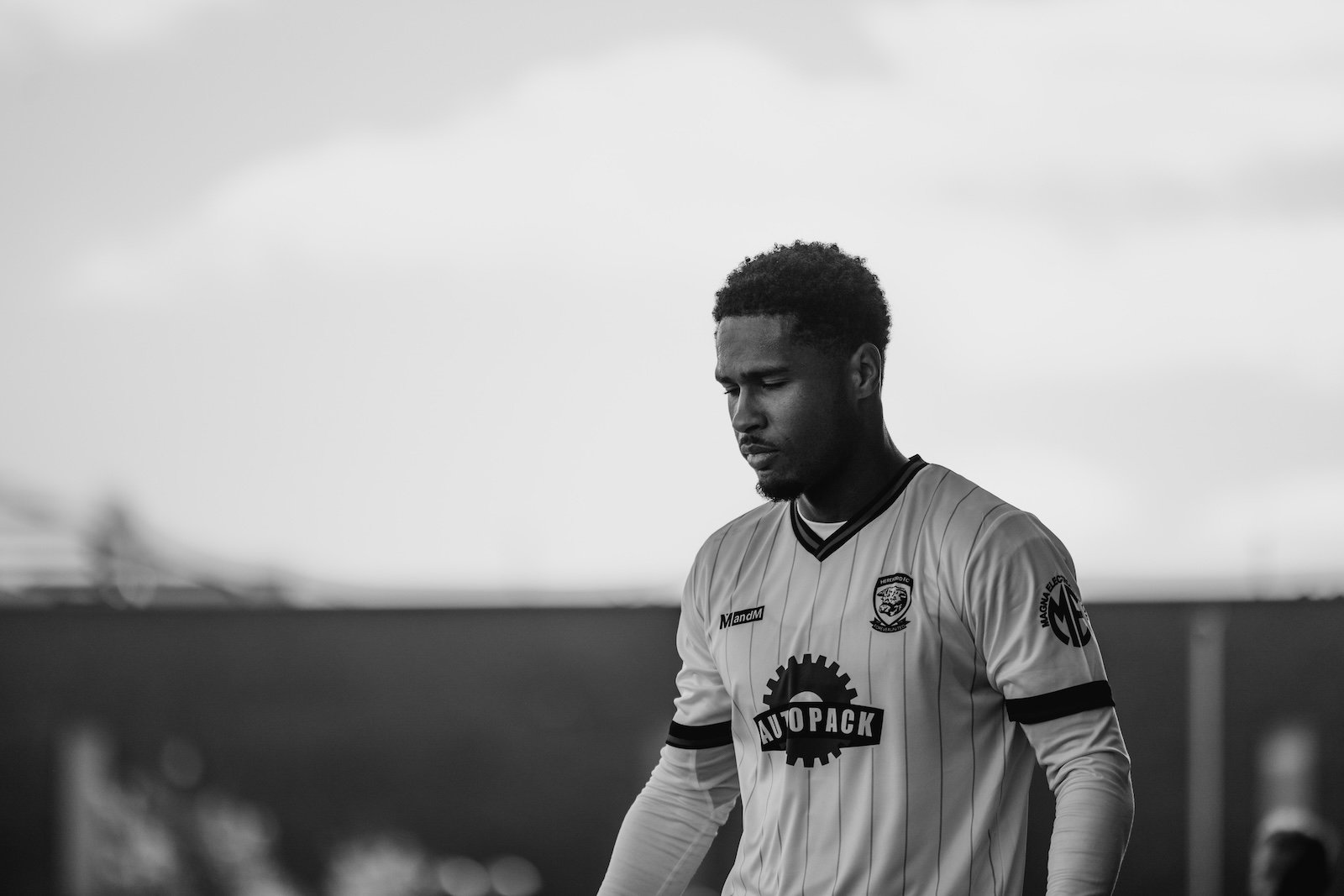 A player seen from behind in driving rain, shirt number eighteen lit against a dark stand