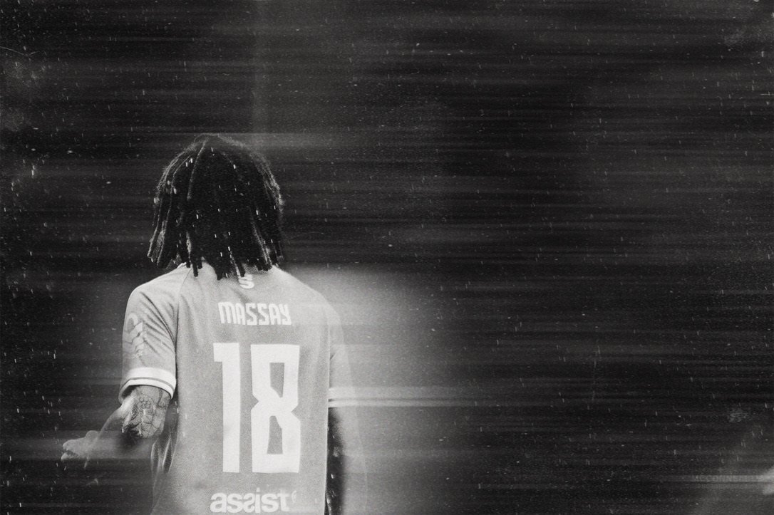 A player seen from behind in driving rain, shirt number eighteen lit against a dark stand
