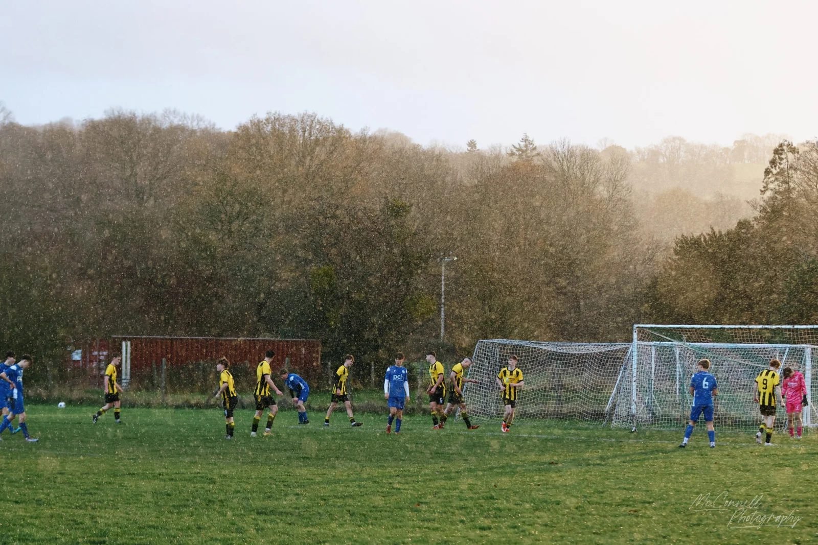 Wide view of a match continuing through a rain shower