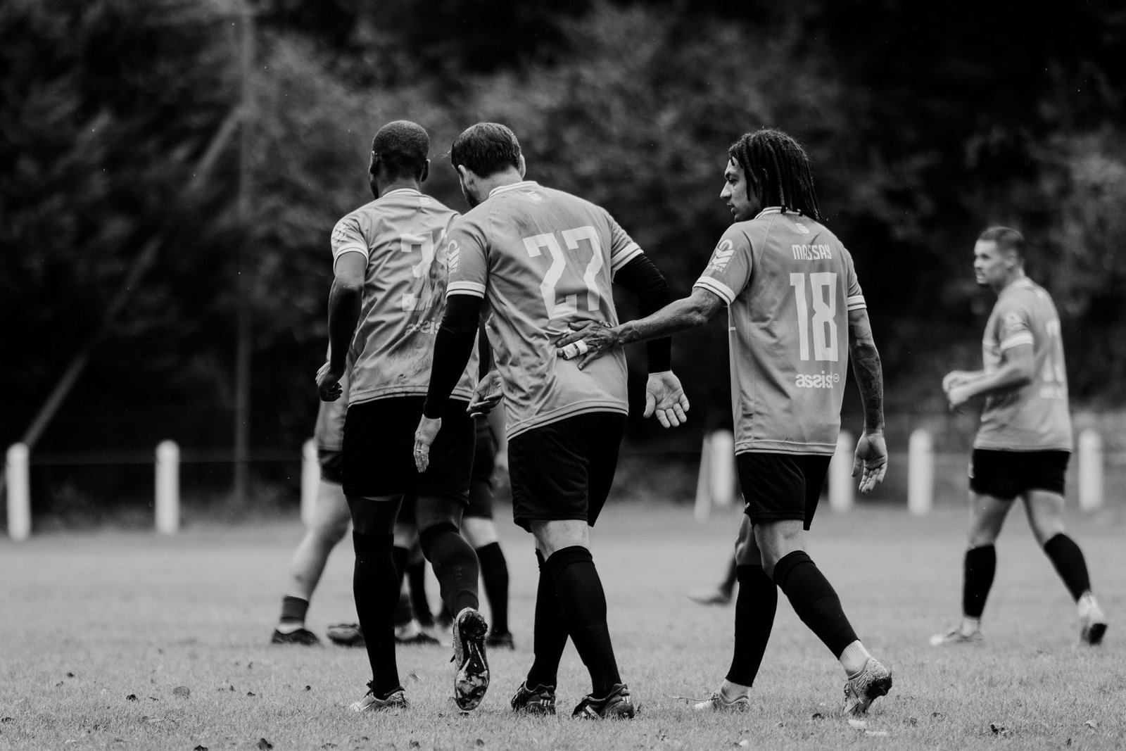 Three team-mates walking back to the halfway line together